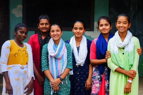 Group of adolescent girls standing together and smiling, representing menstrual care awareness, girls’ health, dignity, and empowerment.